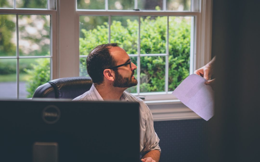 Man sitting discussing bias in performance reviews with standing colleague