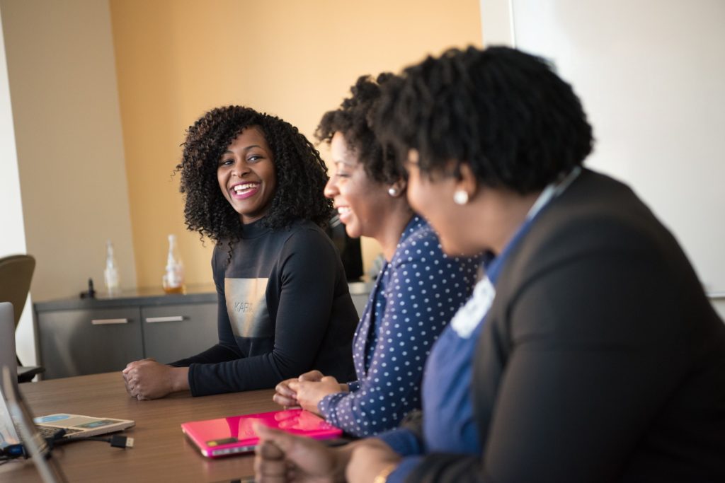 Three Black women smiling discussing employee engagement ideas