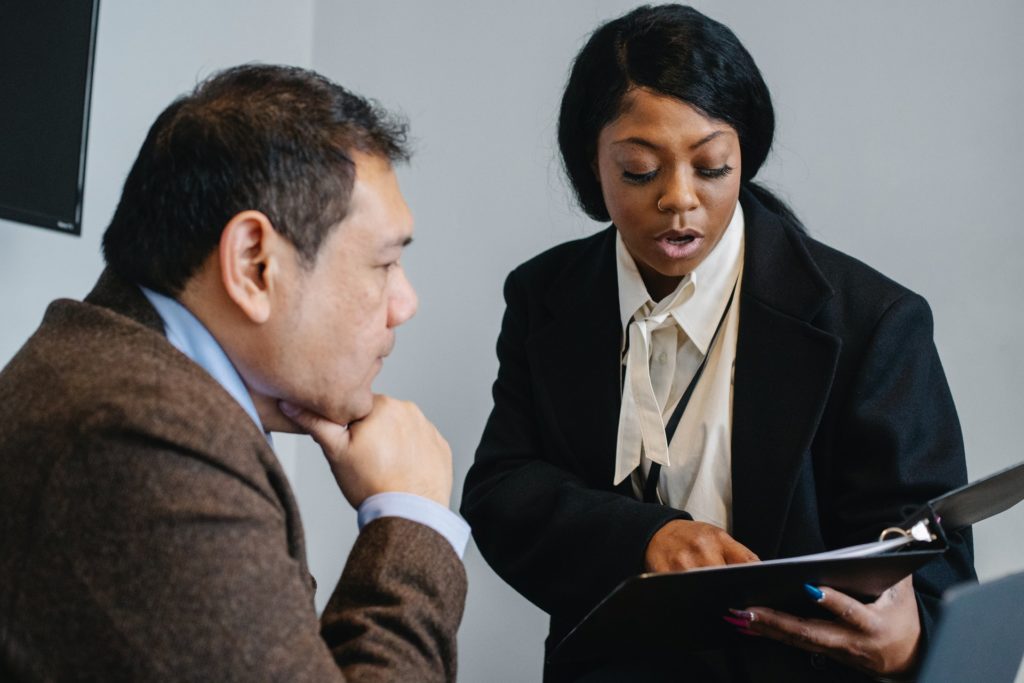 Helpful woman colleague showing review template to man