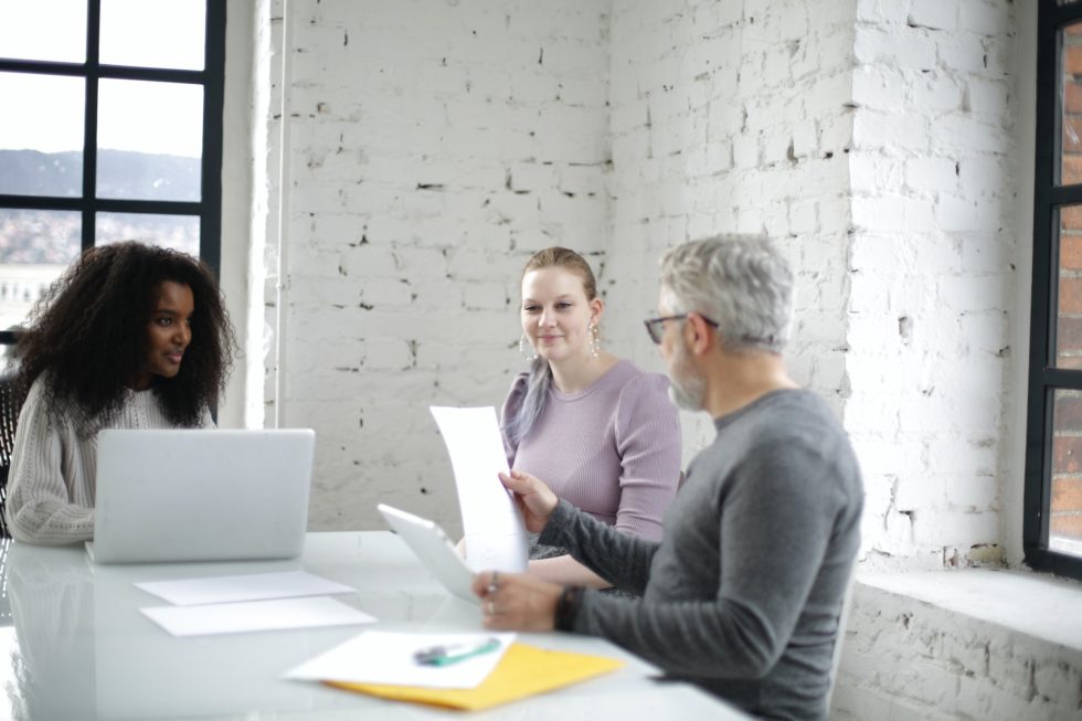 Inclusive group of three colleagues discussing a project review