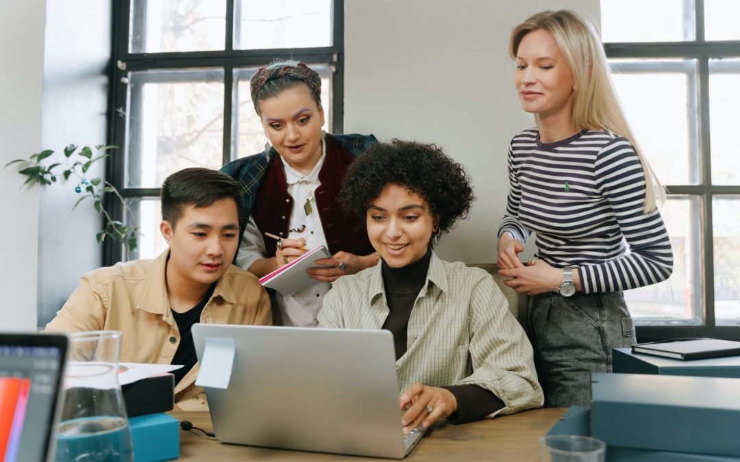 Four colleagues reviewing employee motivation survey on laptop