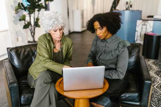 Black woman and older white woman discuss HR analytics on laptop