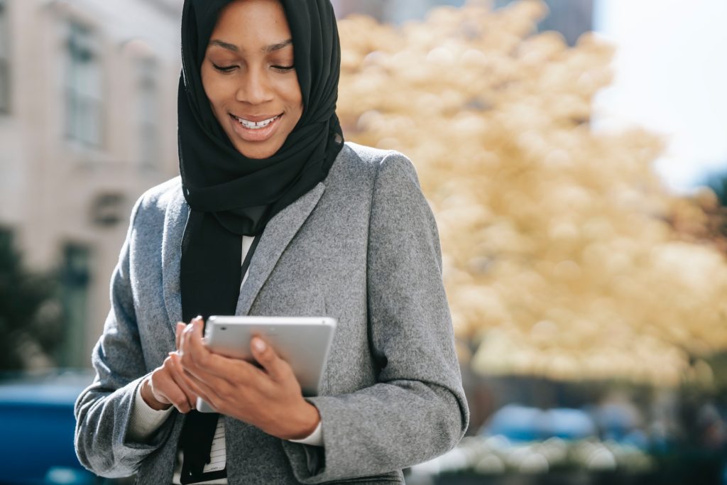 Black woman chief happiness officer in hijab smiling at tablet