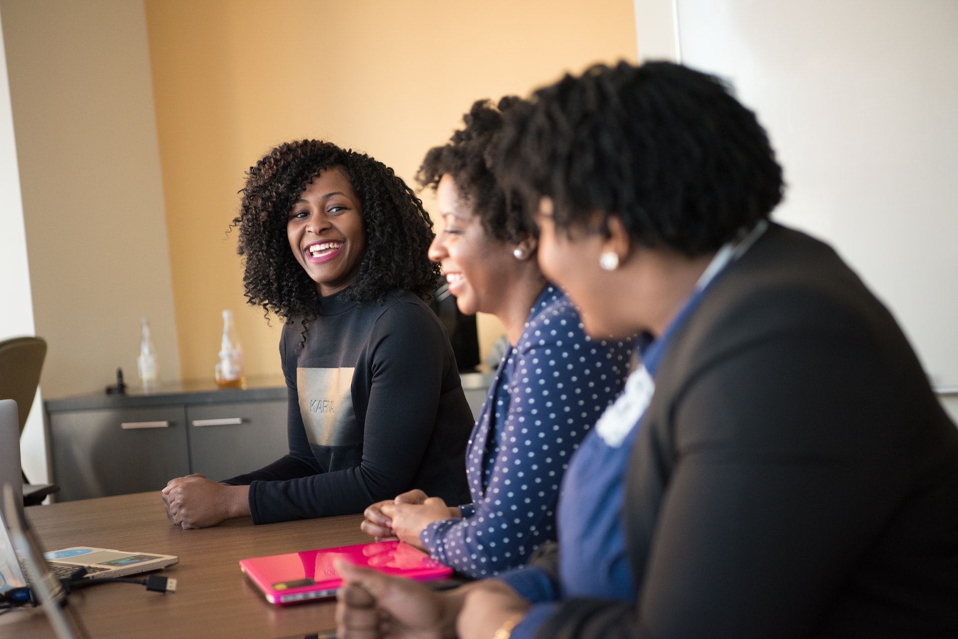 Three professional Black women happily discussing strategy execution