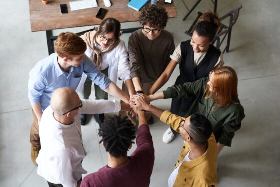Group of diverse colleagues putting hands together in huddle