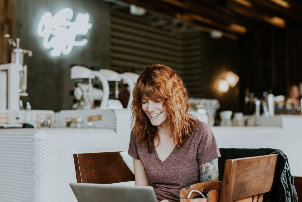 Woman smiling at laptop, happy to do workplace people experience