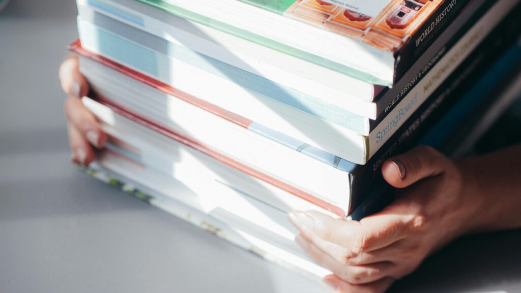 A person holding a stack of books