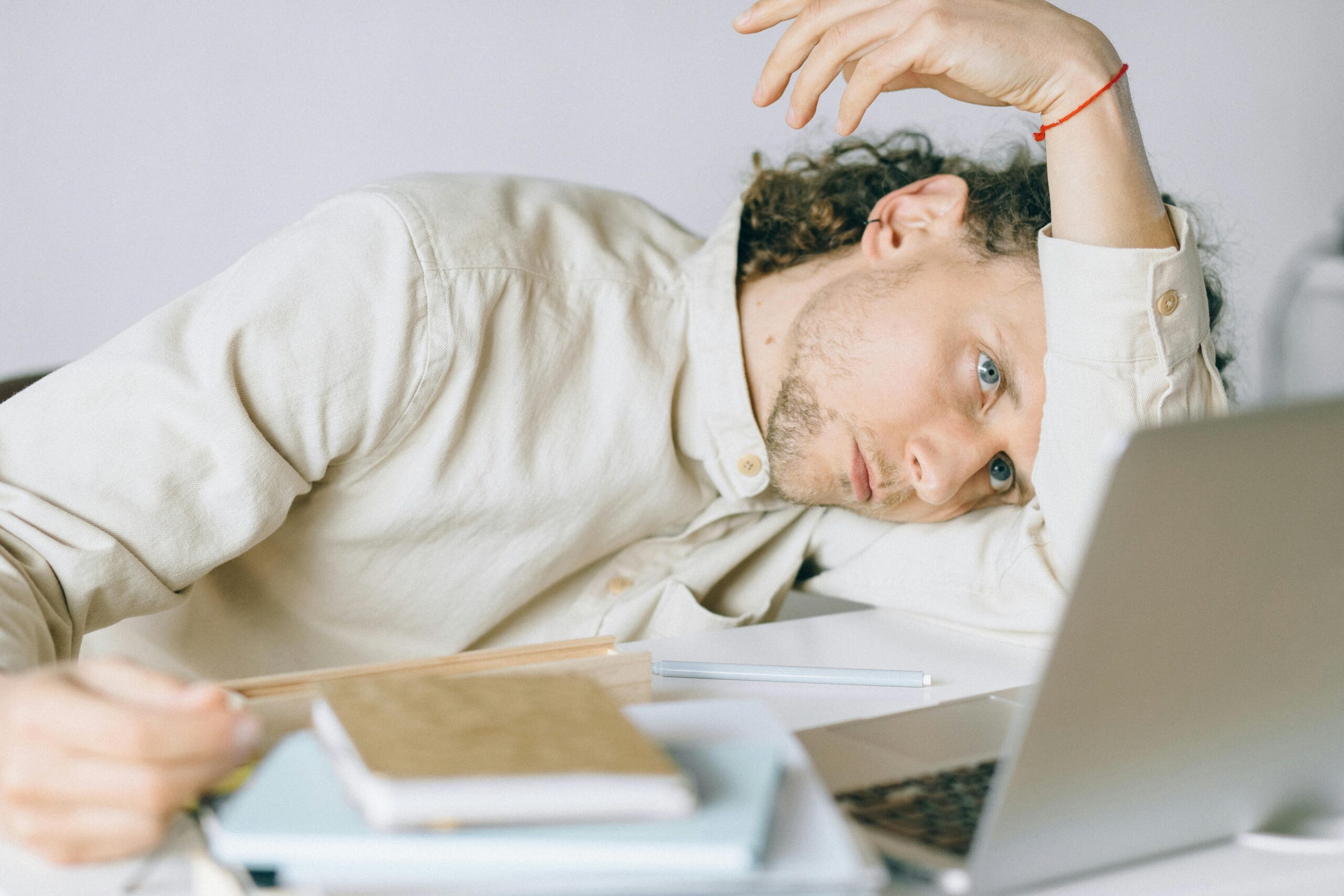 An overworked employee is crouching over his laptop