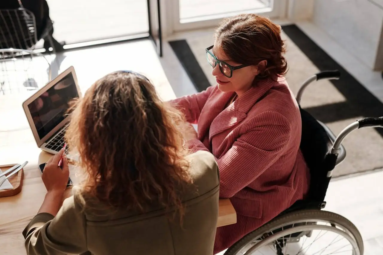 woman-in-red-sweater-sitting-on-wheelchair A manager and an employee having a one-on-one meeting
